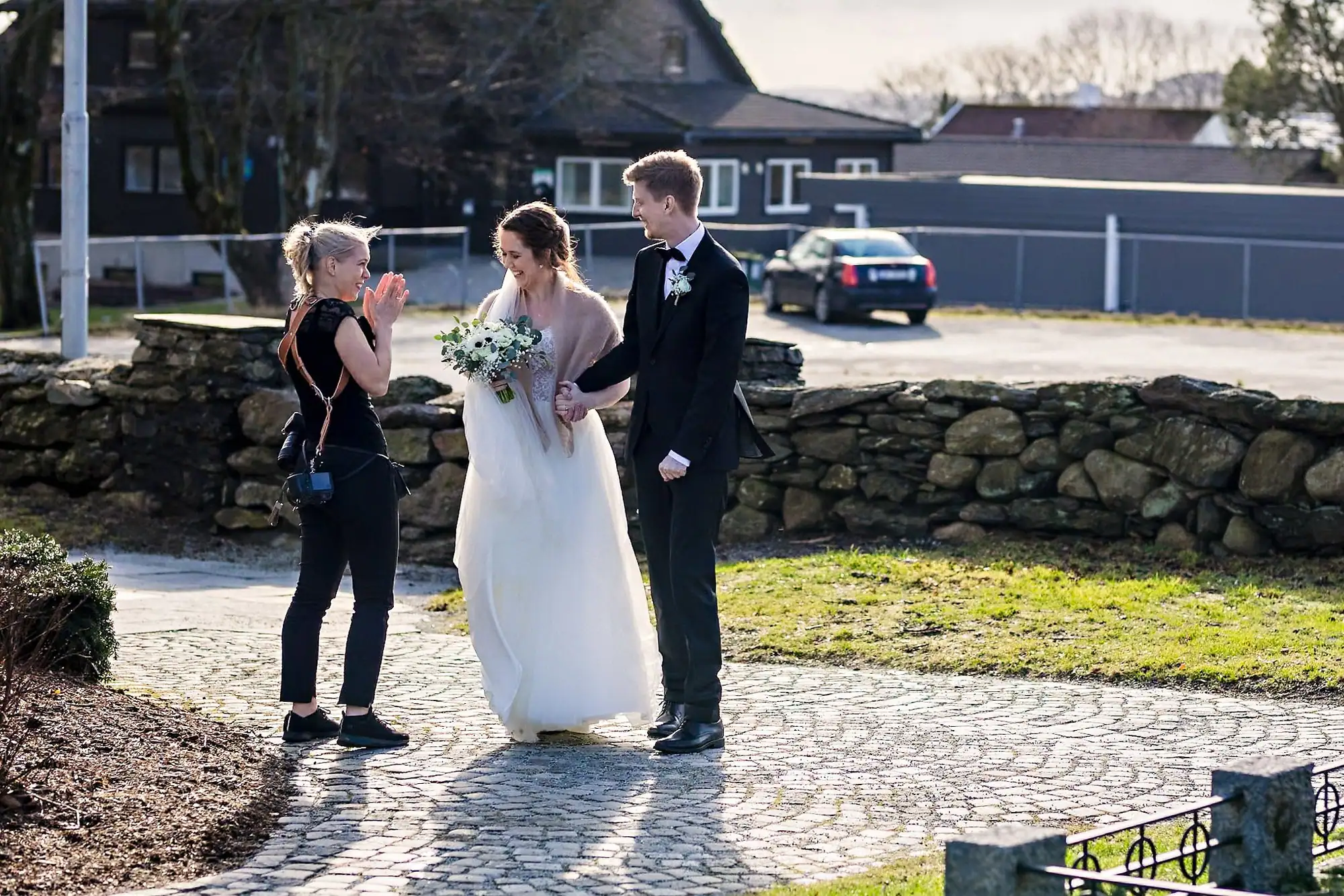 Marte Bjørgum fotograferer et brudepar ute ved en steinmur
