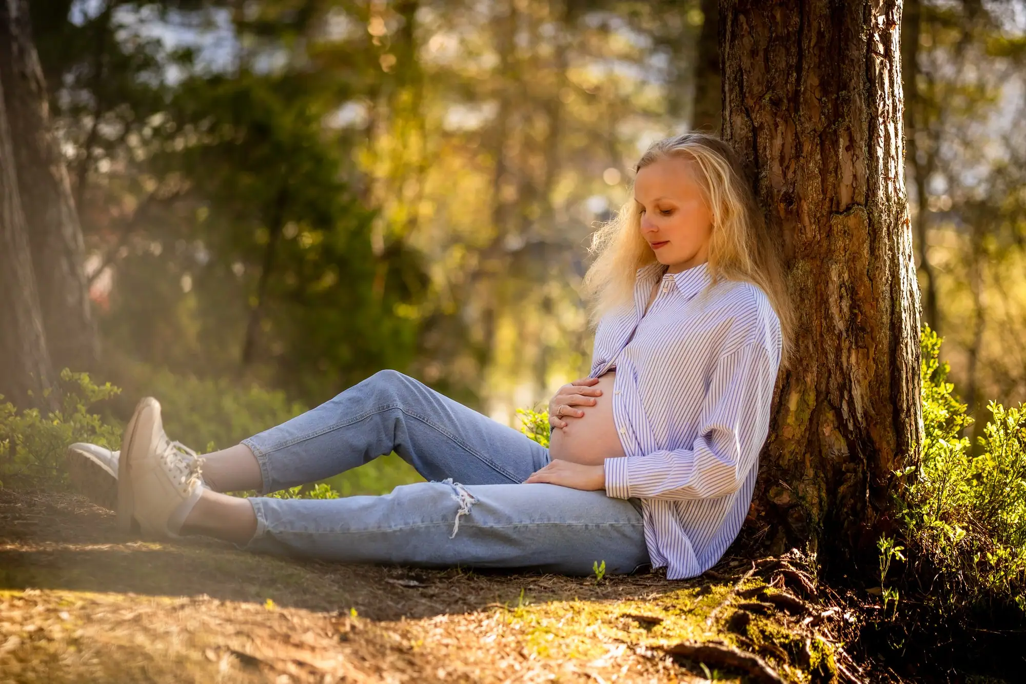 Gravidfotografering ute, kvinne med rund mage i kveldslys