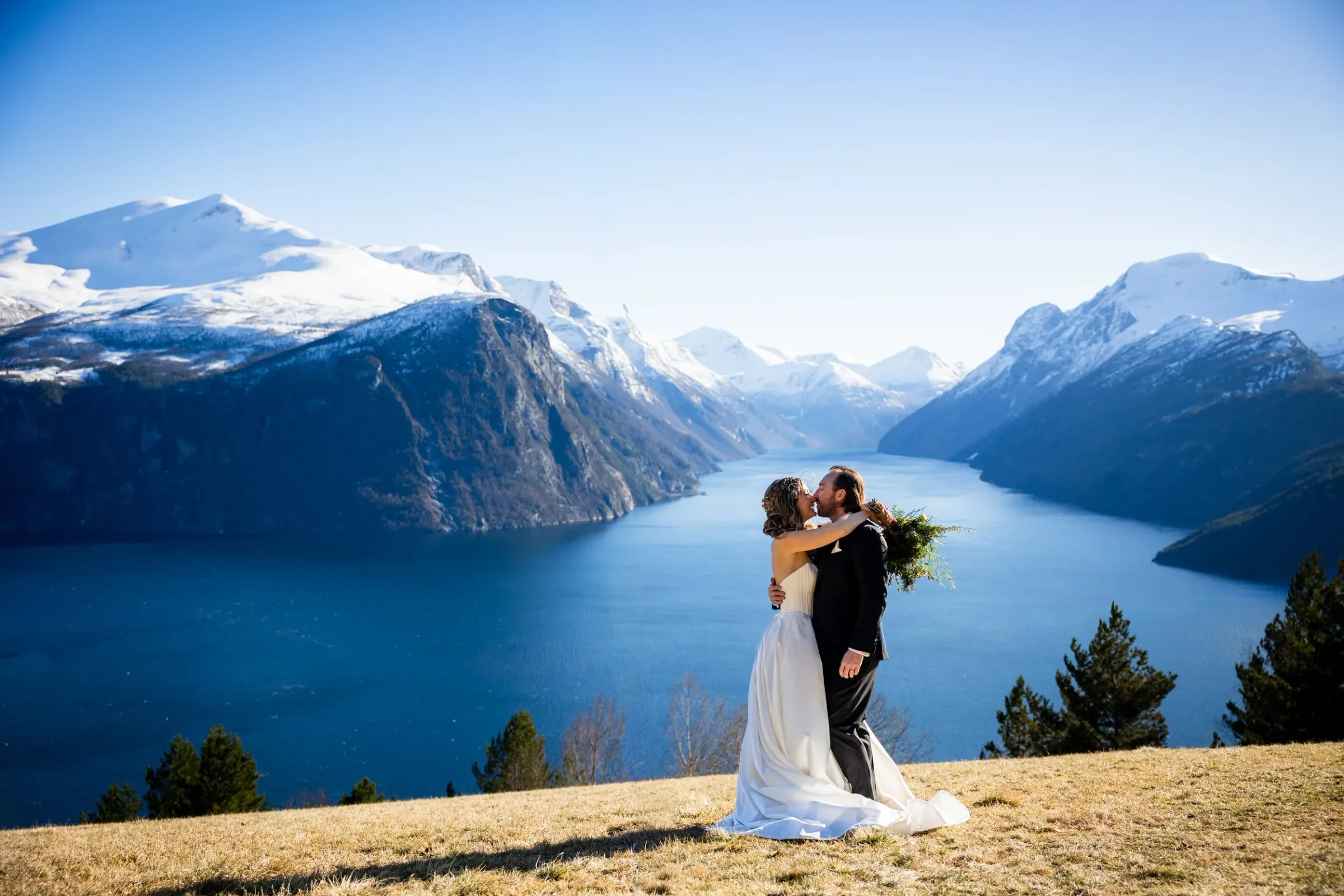 Brudepar tett sammen ved Storfjorden i varmt kveldslys, fotografert av Marte Bjørgum. Liabygda, Norge, fjord og fjell. Bryllup 
