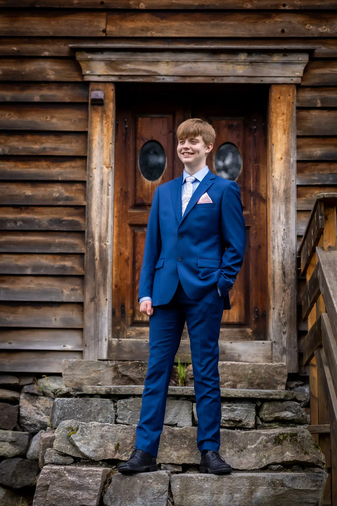 Konfirmant i dress ved gammel dør, fotografert av Marte Bjørgum