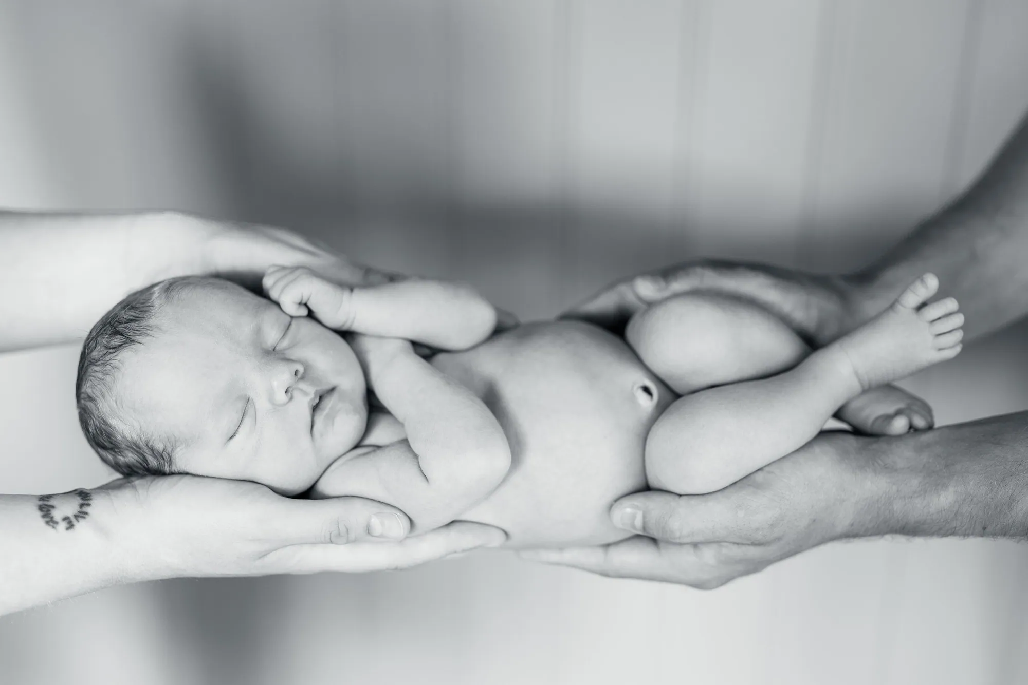 Nyfødtfotografering hjemme, foreldre holder sin nyfødte baby