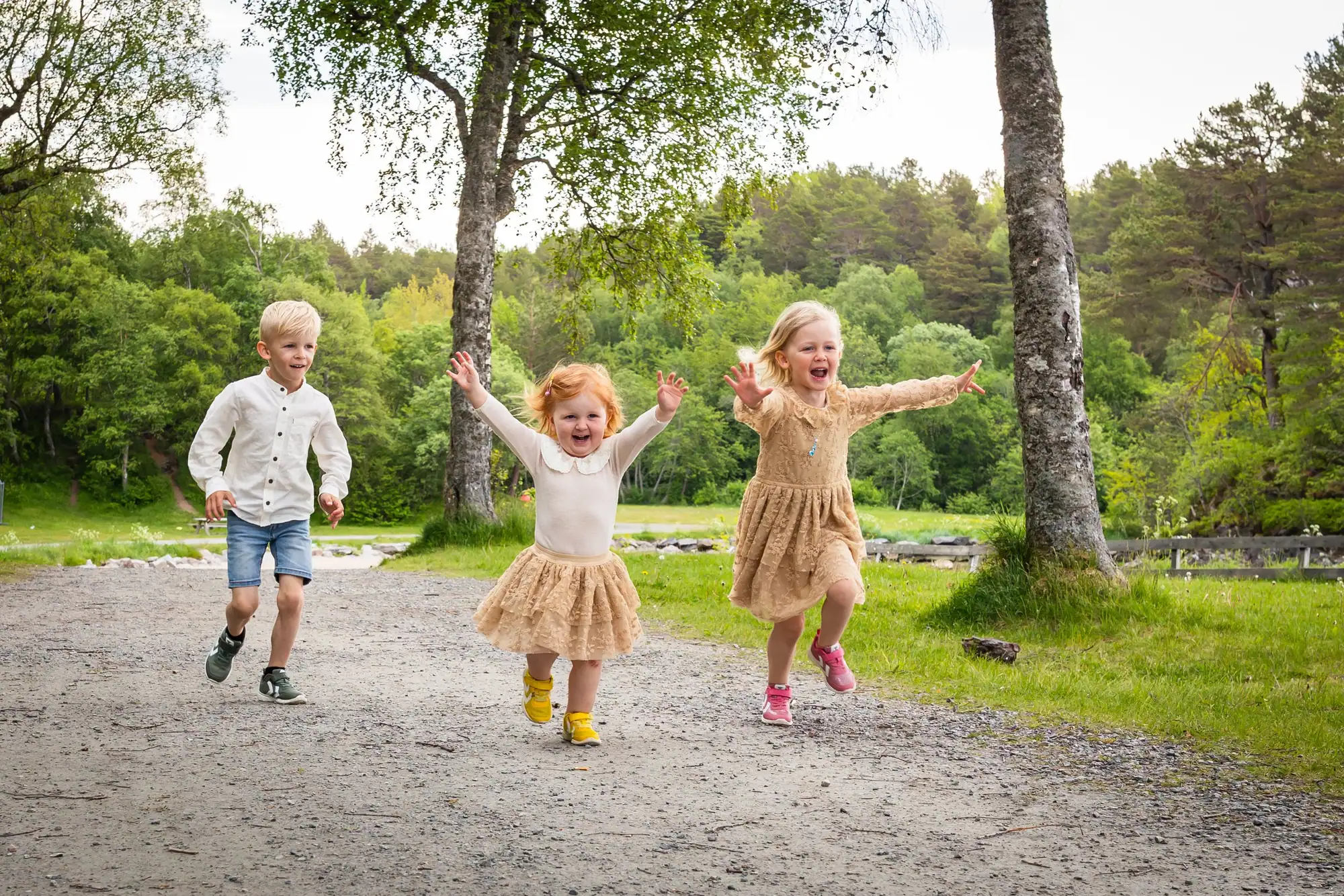 To søsken som løper og leker sammen ute på et jorde